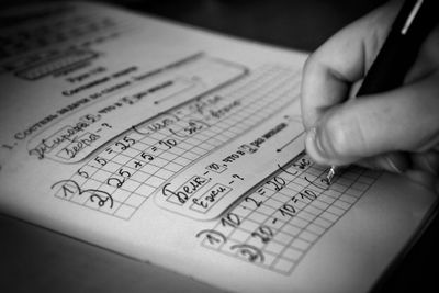 Close-up of human hand writing in book