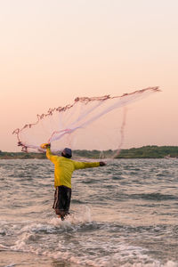 Man fishing in river against clear sky