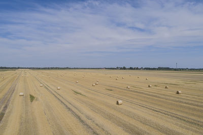 Hay bales on field against sky