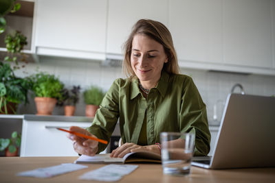 Portrait of smiling woman using laptop while sitting on table