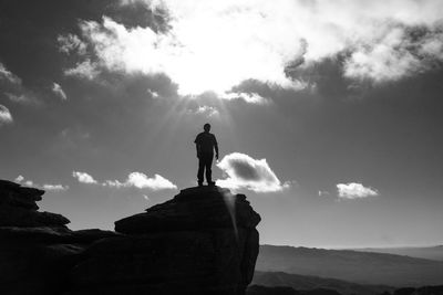 Rear view of silhouette woman standing on cliff against sky