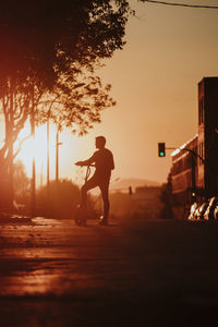 Silhouette man standing on street against sky during sunset