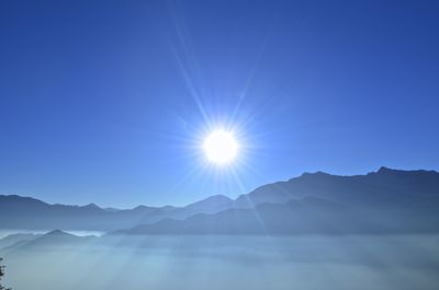 Scenic view of mountains against blue sky on sunny day