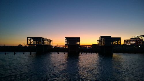 Scenic view of sea by buildings against clear sky during sunset