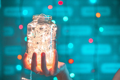 Close-up of woman holding illuminated glass jar