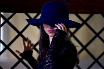 Close-up of woman wearing hat against fence