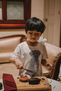 Boy holding food on table at home