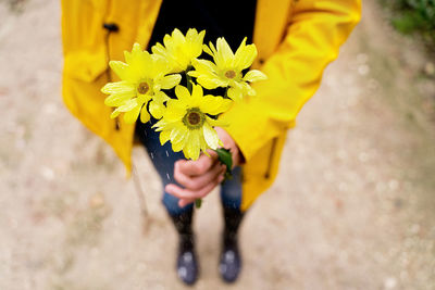 Low section of woman holding yellow flower
