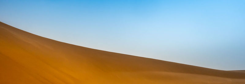 Low angle view of desert against clear blue sky