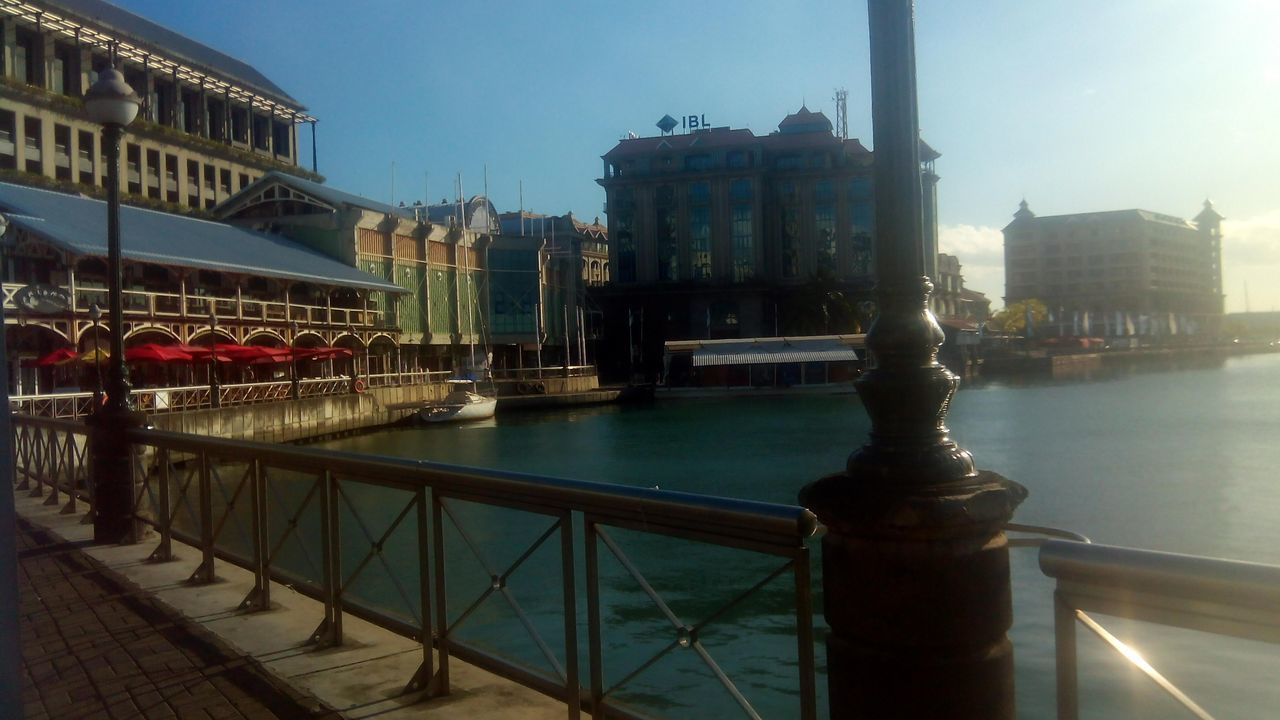 architecture, built structure, railing, building exterior, water, river, bridge - man made structure, city, connection, sky, canal, clear sky, metal, transportation, outdoors, no people, day, bridge, building, reflection