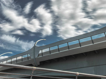 Low angle view of bridge by building against sky