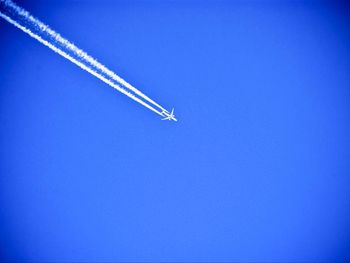 Low angle view of airplane flying against clear blue sky