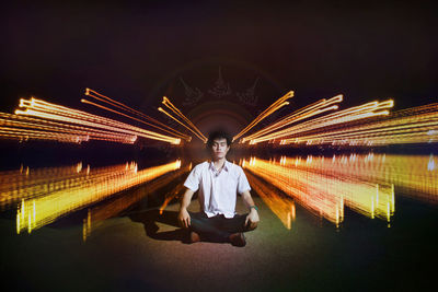 Man sitting on illuminated umbrella at night