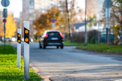 Poles at the traffic safety speed bumps in residential area, blurred background with a car, closeup
