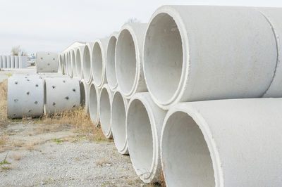 Stacked pipes on field against sky