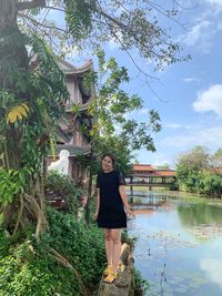 Portrait of woman standing by plants against trees