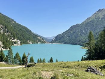 Scenic view of lake and mountains against clear blue sky