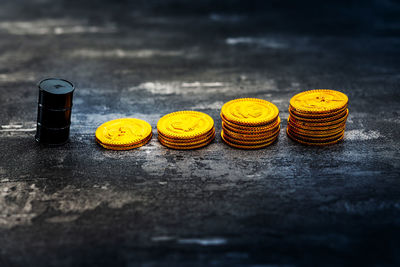 Close-up of miniature black barrel and gold coins on table