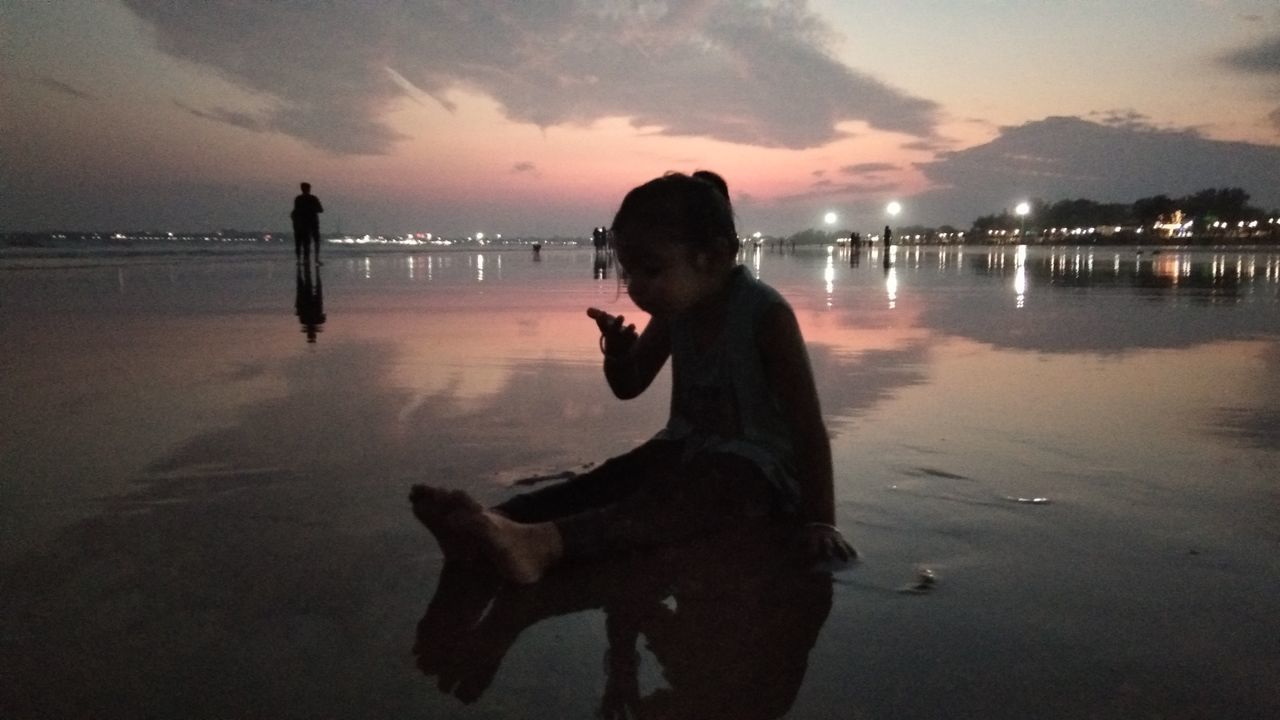 SIDE VIEW OF MAN STANDING ON BEACH AGAINST SKY