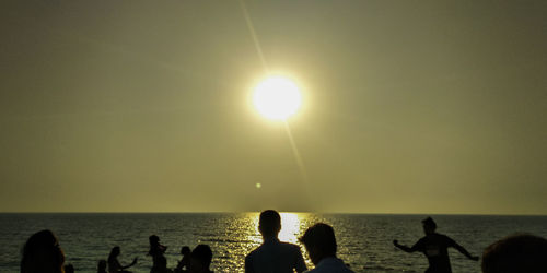 Silhouette people on beach against sky