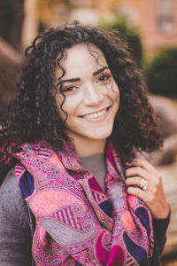 Close-up portrait of young woman with curly hair standing outdoors