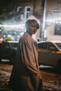 Rear view of man looking at illuminated city at night