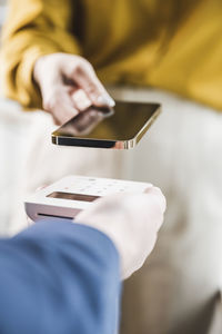 Hand of businesswoman paying through smart phone on credit card reader