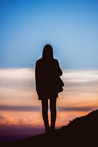 Silhouette of woman against sunset sky