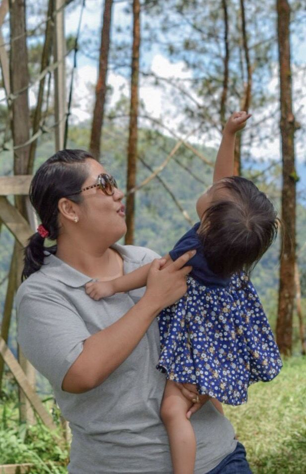 MOTHER AND DAUGHTER STANDING AGAINST TREES