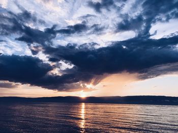 Scenic view of sea against dramatic sky during sunset