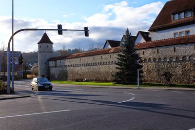 Cars on road by buildings against sky in city