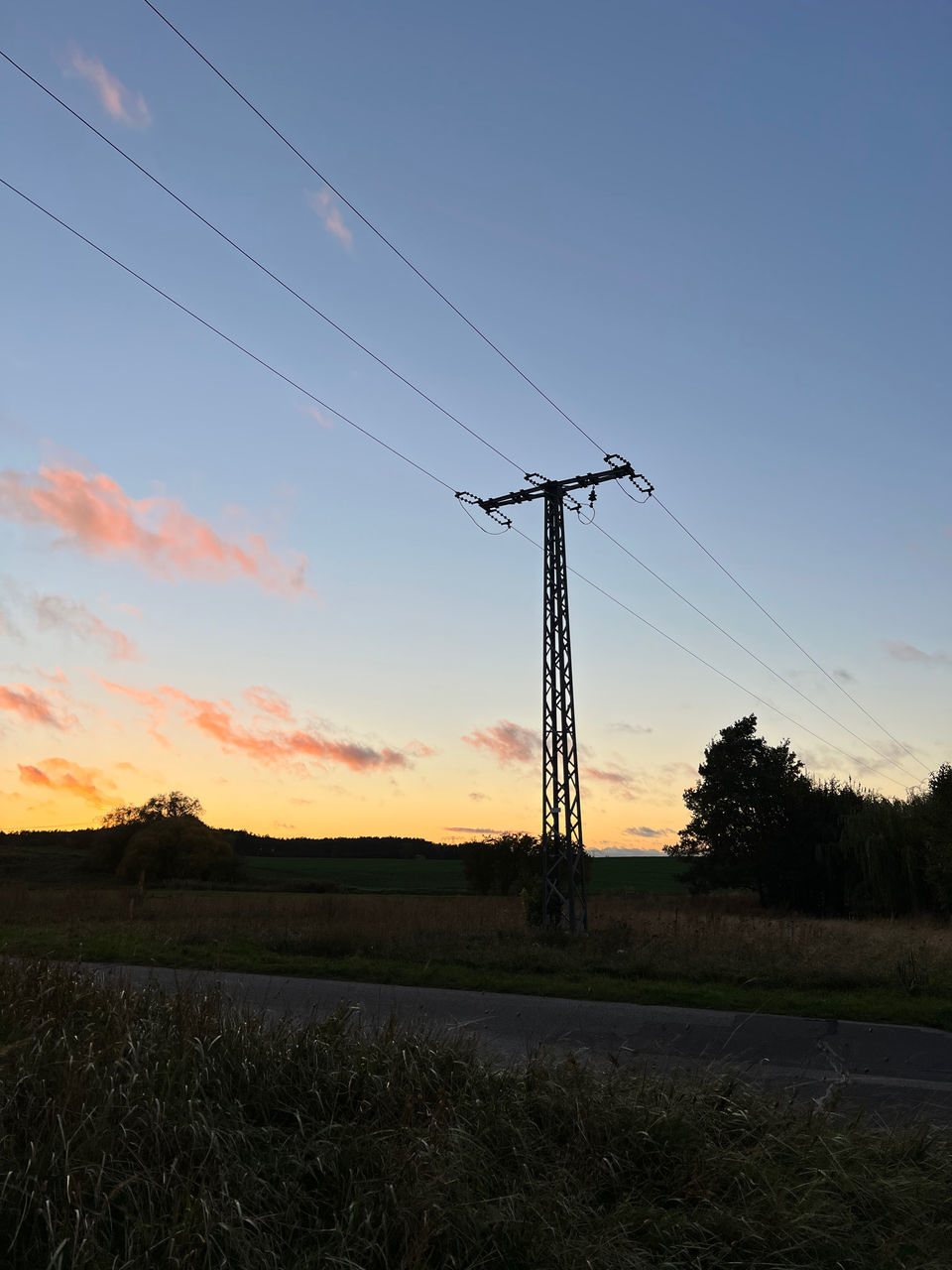 ELECTRICITY PYLONS ON FIELD AGAINST SKY AT SUNSET