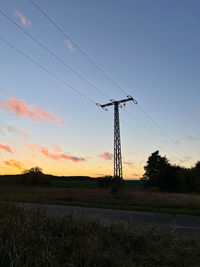 Electricity pylon on field against sky during sunset