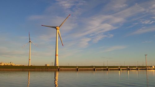 Windmills on water against sky