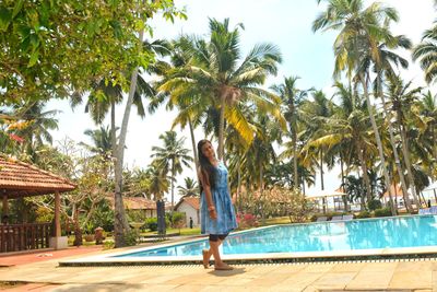 Woman by palm trees in swimming pool