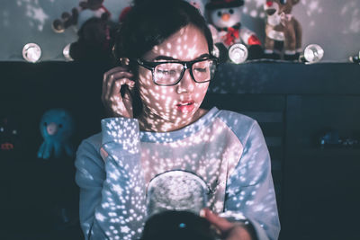 Young woman wearing eyeglasses looking down at illuminated room