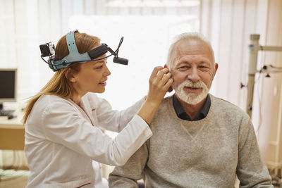 Ent physician examining ear of a senior man