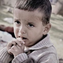 Close-up of sad boy with finger in mouth