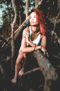 Young woman sitting on tree at forest