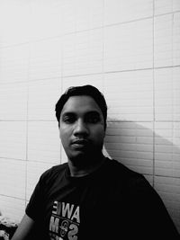 Portrait of young man standing against wall