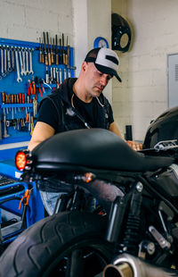 Man repairing motorcycle in garage