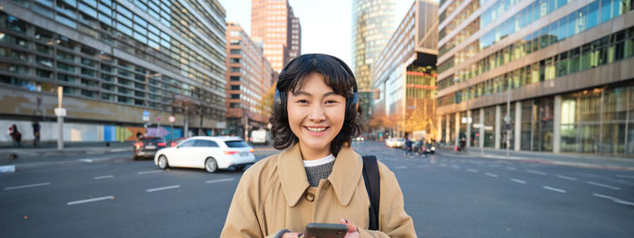 Portrait of young woman standing in city