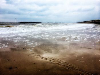 Close-up of wet beach against sky