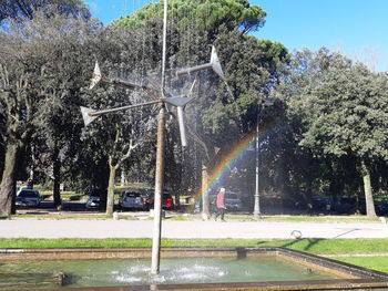 Fountain in park by street against sky