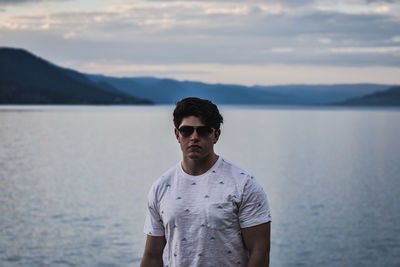 Young man wearing sunglasses on sea against sky