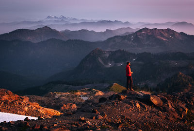 Side view of man standing on mountain against sky during sunset