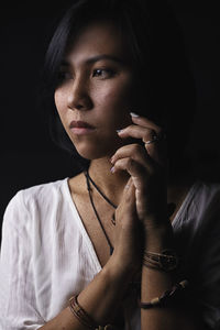 Close-up portrait of young woman against black background