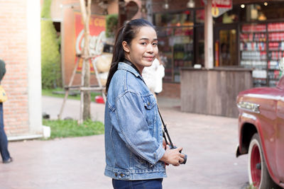 Portrait of young woman standing in city