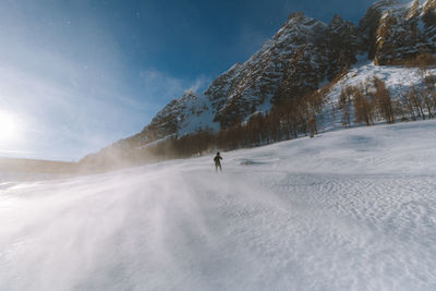 Person walking on snow covered mountain against sky