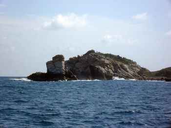 Rock formation in sea against sky